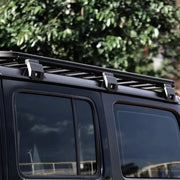 A Jeep Wrangler driving down a scenic road with a bike rack attached to the roof rack.